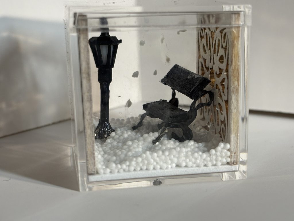 MIniature with snow, a lamppost and empty bench